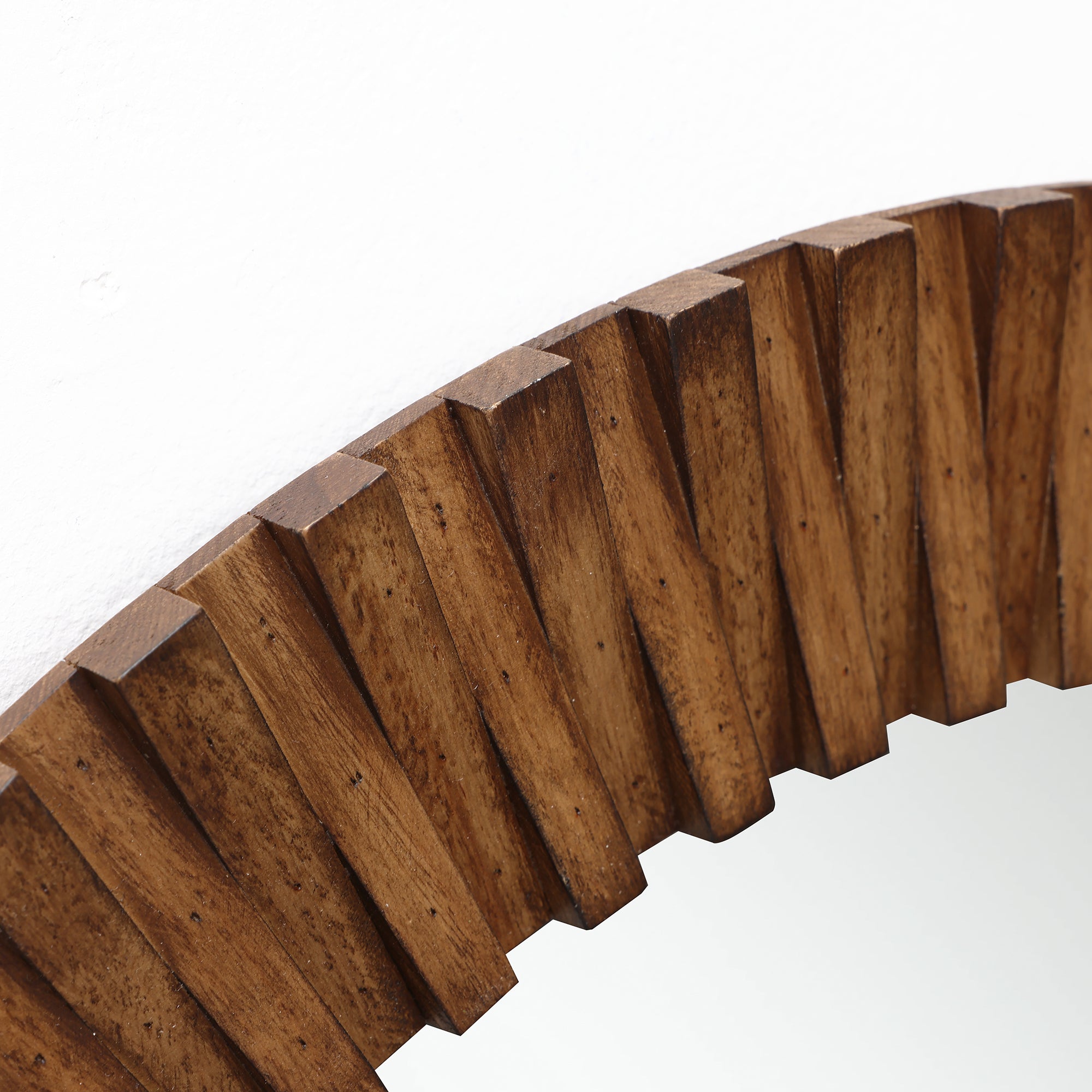 Close-up of a round wall mirror with a thick, ridged oak wood frame featuring a striking diagonal pattern.