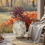 Terracotta Vase with rustic finish placed on a round mat beside a wooden chair and beige blanket, filled with red maple branches and framed by autumn foliage for cozy farmhouse décor.