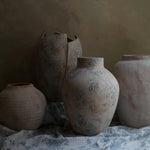 Four textured ceramic vases in varied shapes and sizes are artfully arranged on a patterned cloth, set against a muted background. These exquisite pieces of home decor boast subtle white marble textures that enhance their elegant charm.