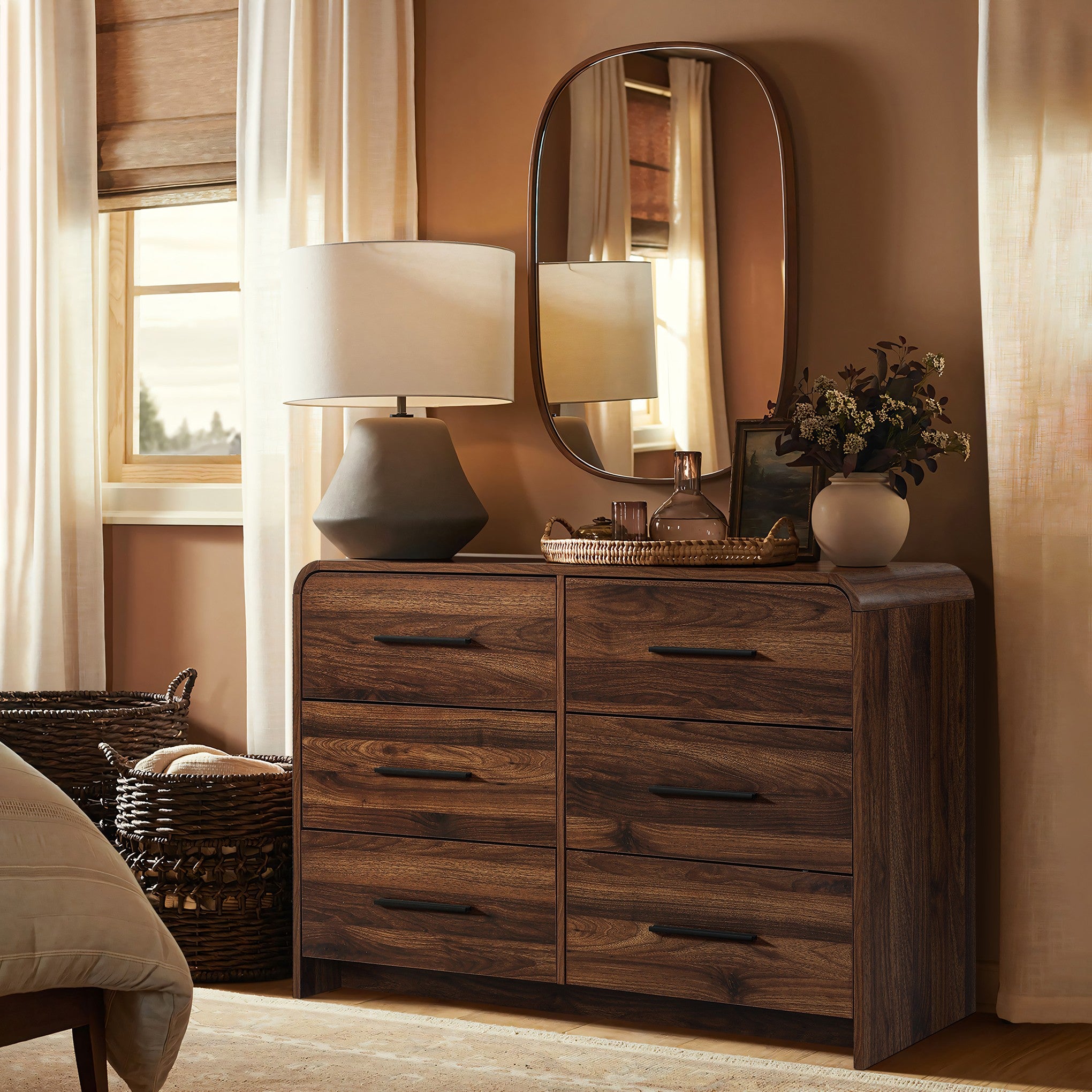 A walnut dresser with six drawers, a table lamp, decorative vases, a round mirror on top.