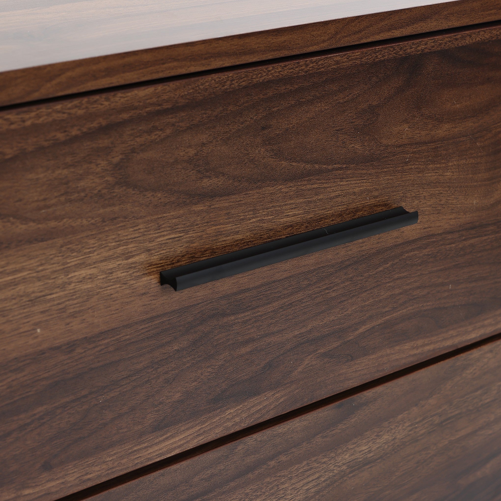 Close-up of a dark walnut dresser drawer with a black horizontal handle.