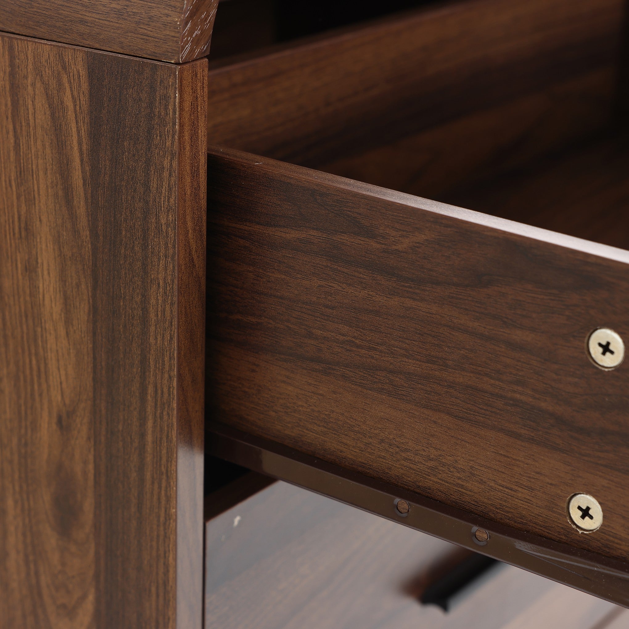 A close-up view of a partially open wooden drawer in a walnut dresser, with two visible screws on the side panel.