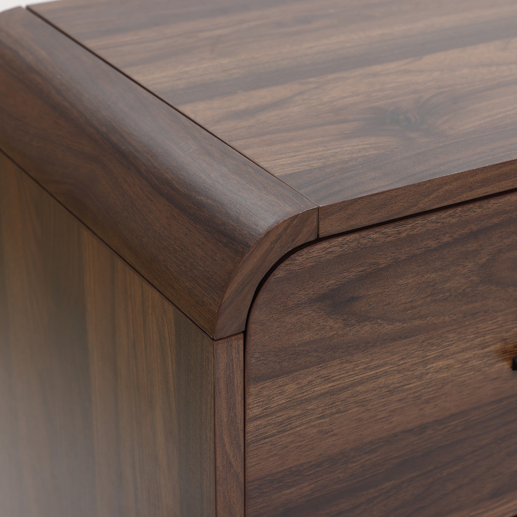 Close-up of the top corner of a walnut dresser with a smooth, rounded edge ,visible wood grain pattern.