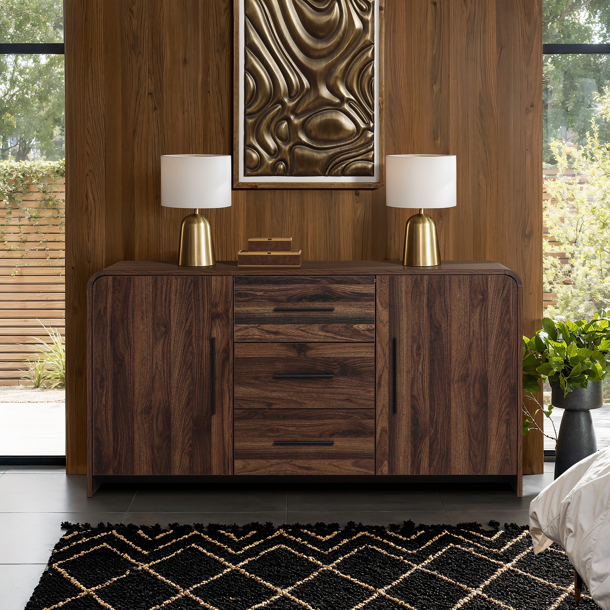 wood sideboard cabinet with drawers, cabinets is placed against wooden wall, topped with2 lamps, books.