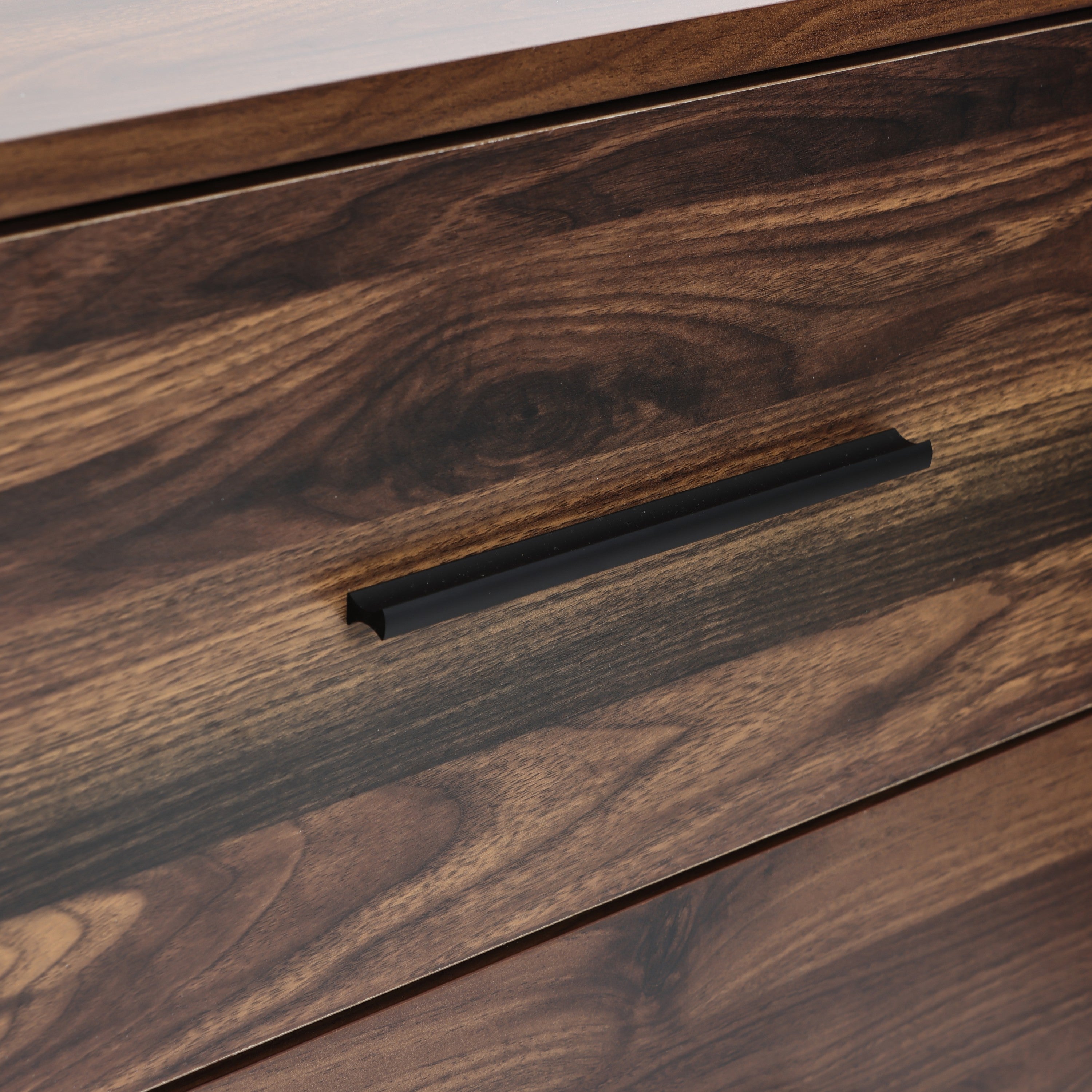 A wood sideboard cabinet drawer with a dark metal handle, showing the wood grain.