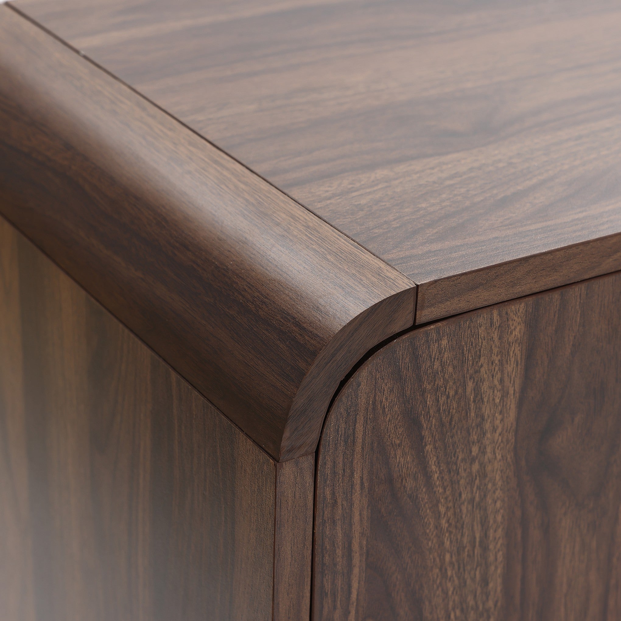 Close-up view of the corner of a wood sideboard cabinet with a smooth, rounded edge and visible wood grain pattern.