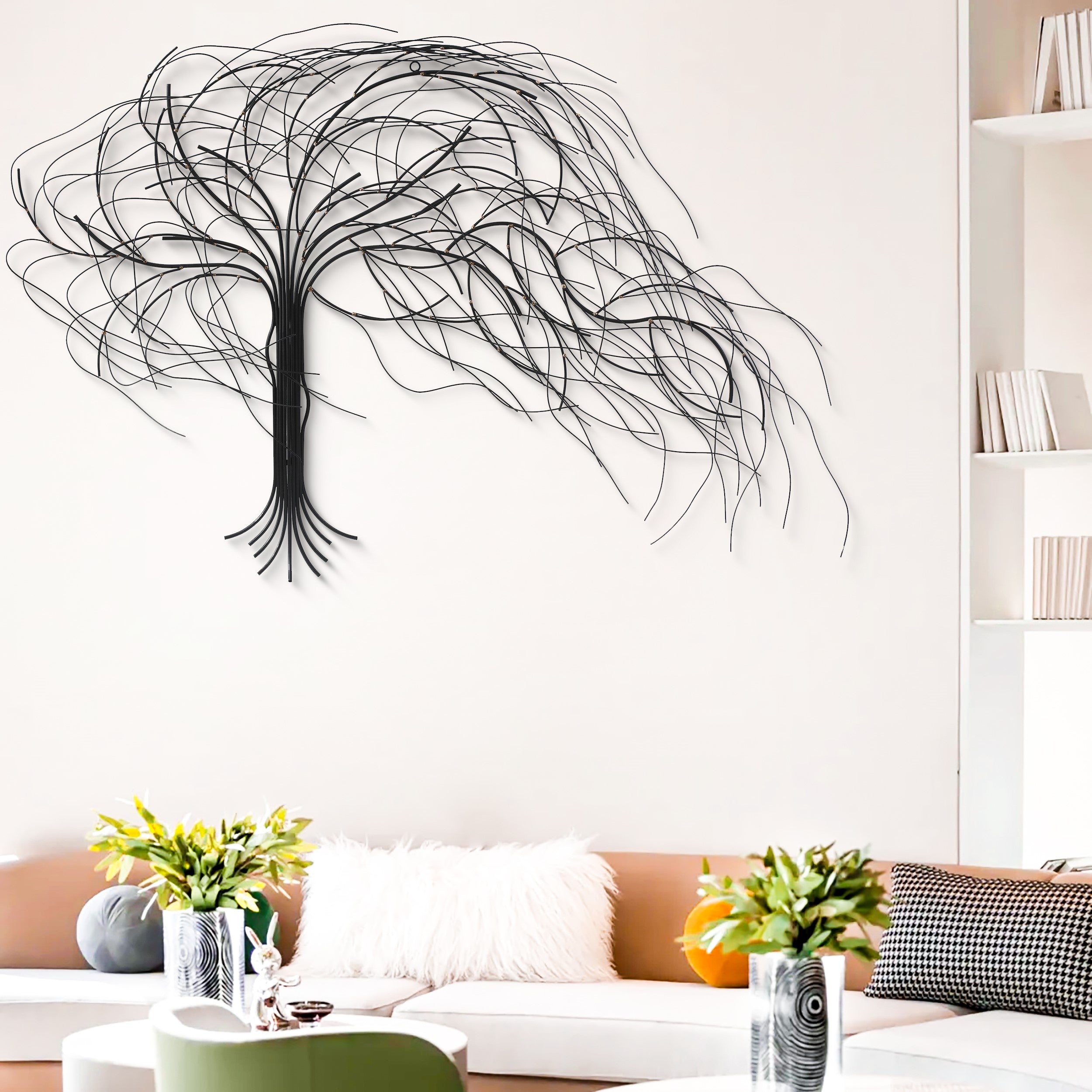 A modern living room with a tan sofa, white furry pillow, vases with flowers, and a striking handcrafted metal tree wall decor on a white wall.