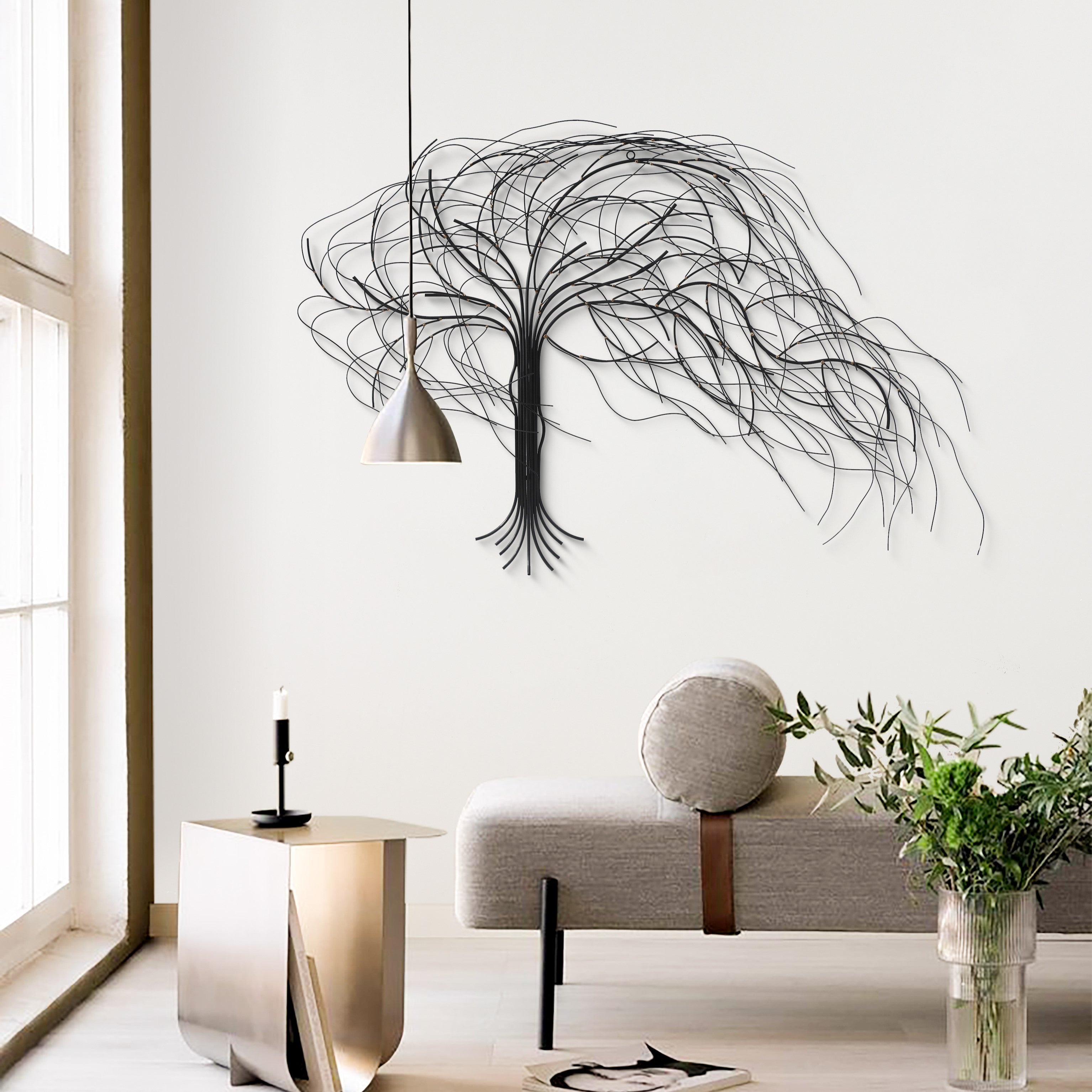 Modern living room with a handcrafted metal tree wall decor, minimalist furniture, a pendant light, and potted plants near a large window.