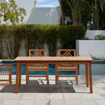 A wooden outdoor dining table with two chairs, crafted from solid Malaysian hardwood with a teak oil coating, sits on a tiled patio beside a swimming pool, surrounded by lush greenery and framed by a white wall.