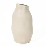 An ivory white ceramic vase with an asymmetrical shape, this accent piece boasts a smooth matte finish, featuring a wavy design and an angled top opening.