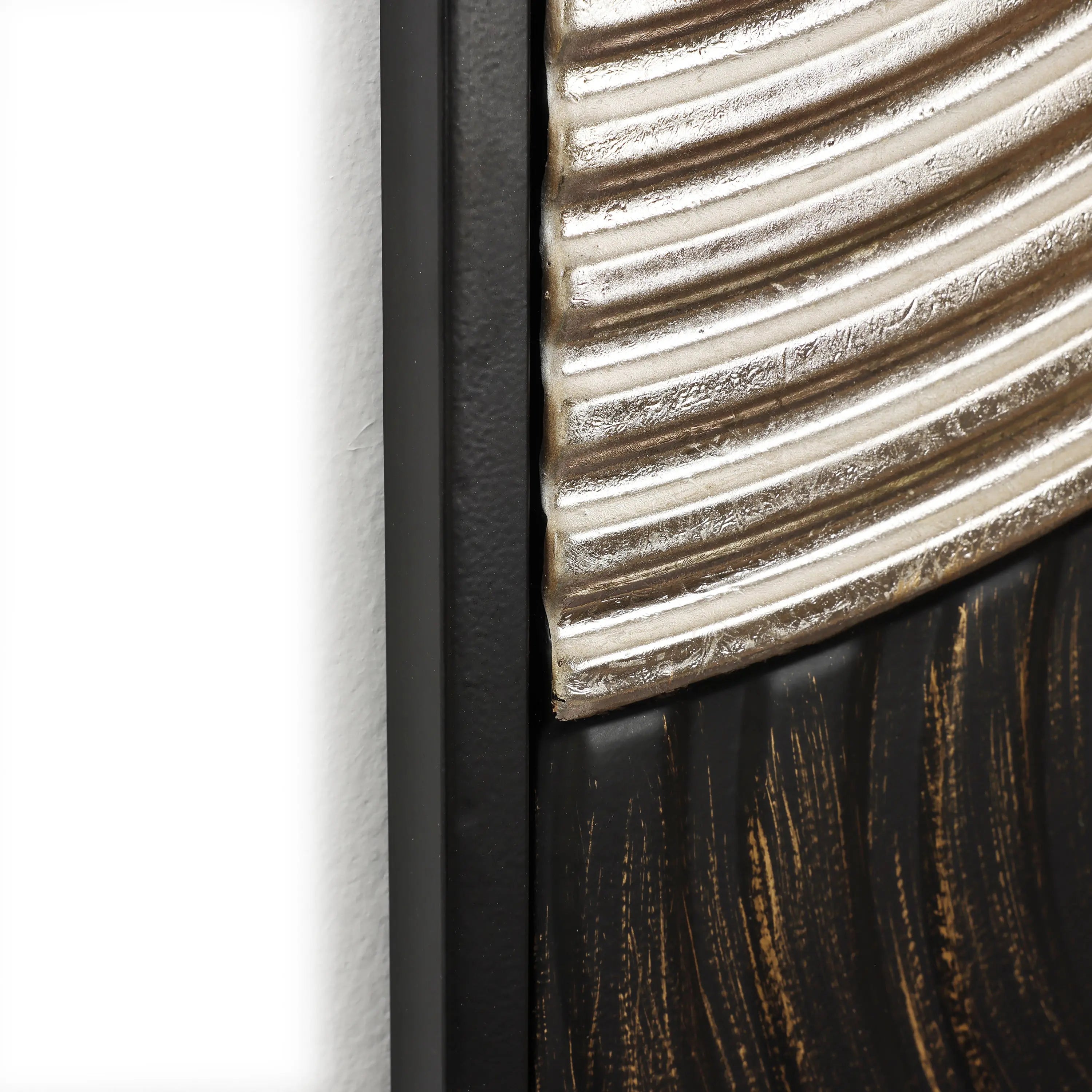 Close-up of an art piece showcasing embossed textures and ridged metallic, dark smooth surfaces, elegantly framed with a sleek black border.