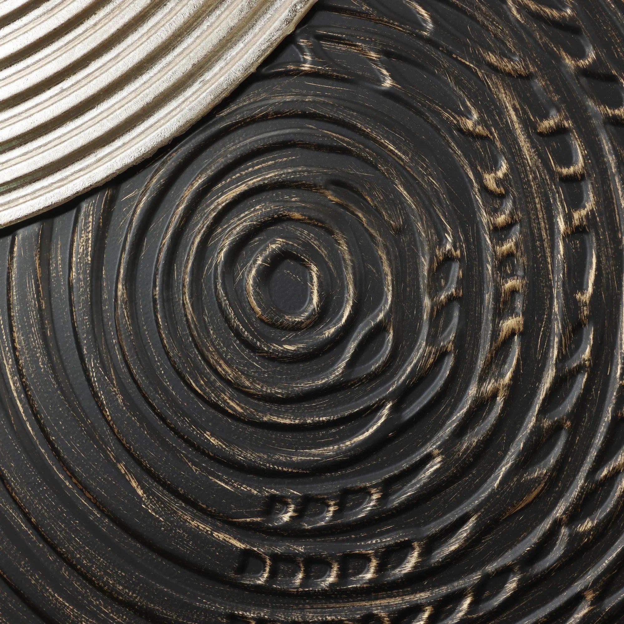 Close-up of a textured, circular wood pattern with black and bronze tones, intersected by a ribbed metallic edge in the top left corner. This captivating art piece, enhanced by embossed textures, adds sophisticated elegance to any wall decor.