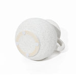 A speckled white ceramic mug with a wide body and a single handle, reminiscent of a decorative jug design, rests upside down on a white surface.