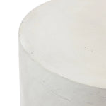 Close-up of the top corner of a smooth, cylindrical cement side table with a minimalist design and an ombre style finish.