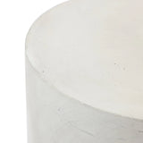 Close-up of the top corner of a smooth, cylindrical cement side table with a minimalist design and an ombre style finish.