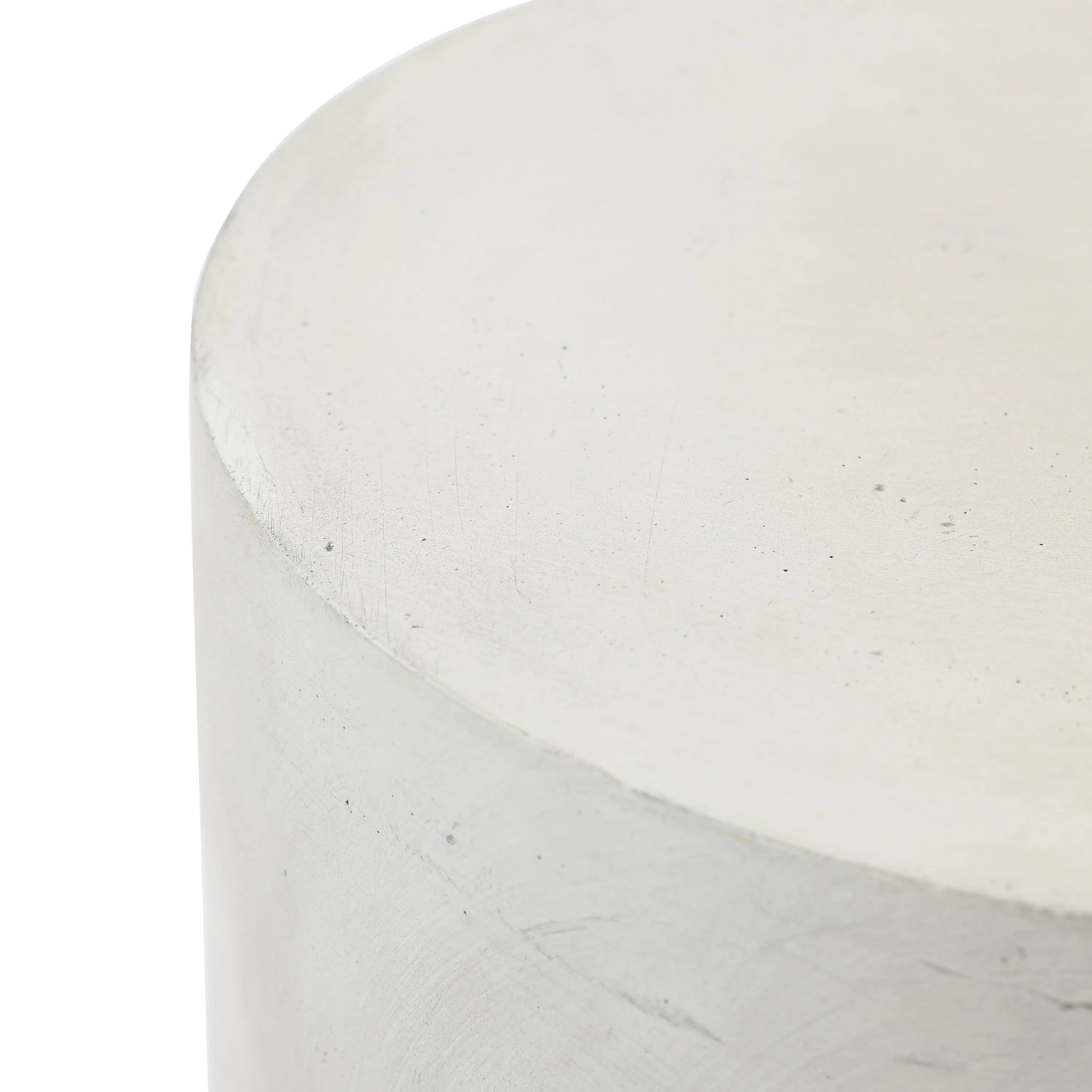 Close-up of the top corner of a smooth, cylindrical cement side table with a minimalist design and an ombre style finish.