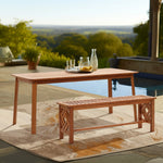 A solid Malaysian hardwood outdoor dining table and bench set grace the patio near the pool, featuring a glass pitcher and cups. Treated with a teak oil coating, this ensemble overlooks a lush green landscape, offering both durability and elegance.