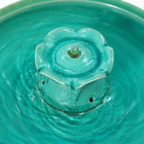 A decorative garden piece, this turquoise ceramic fountain features a flower-shaped top with water gently flowing in two tiers, creating a serene atmosphere.