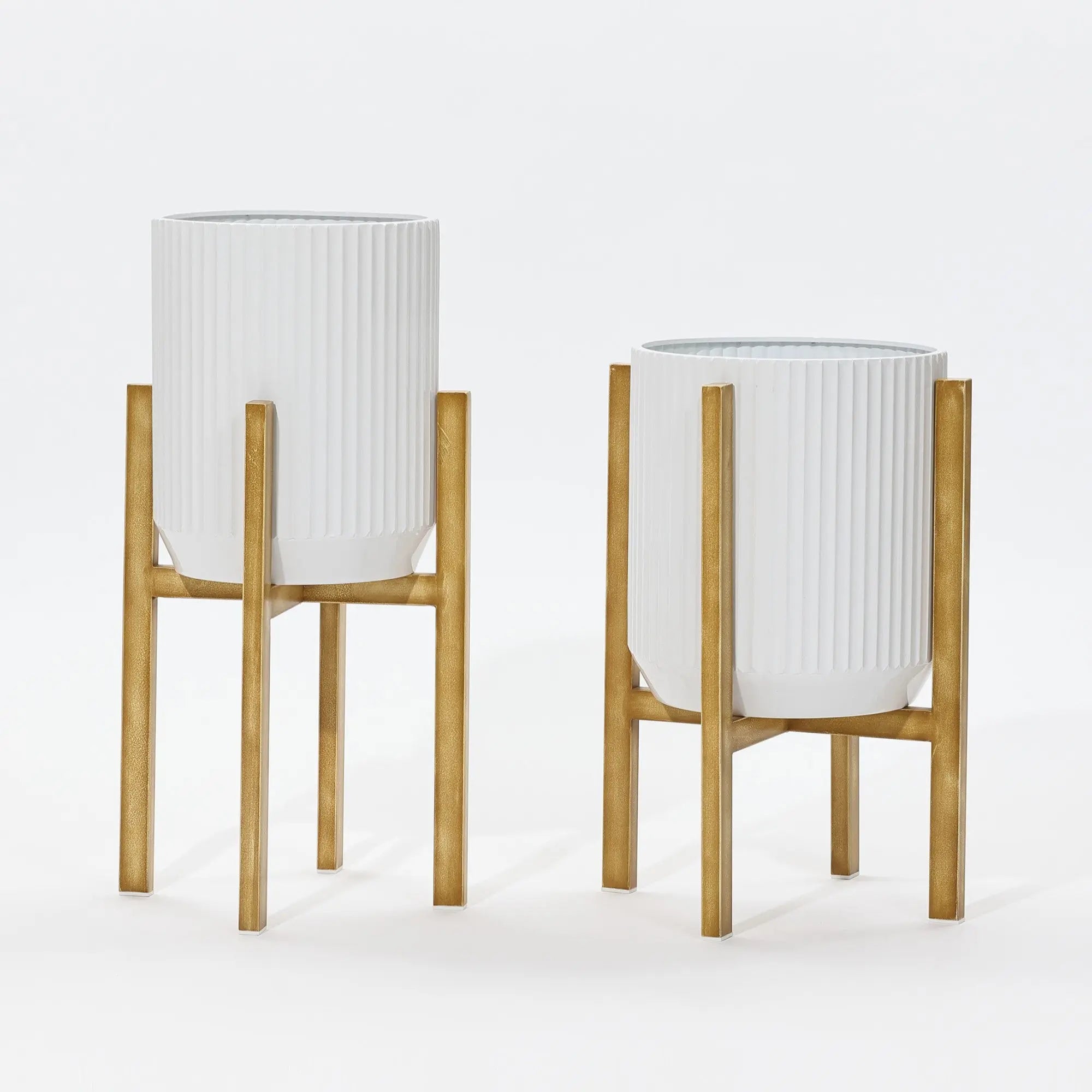 Two modern metal plant pots with ribbed designs stand elegantly against a plain background, each perched on wooden stands.