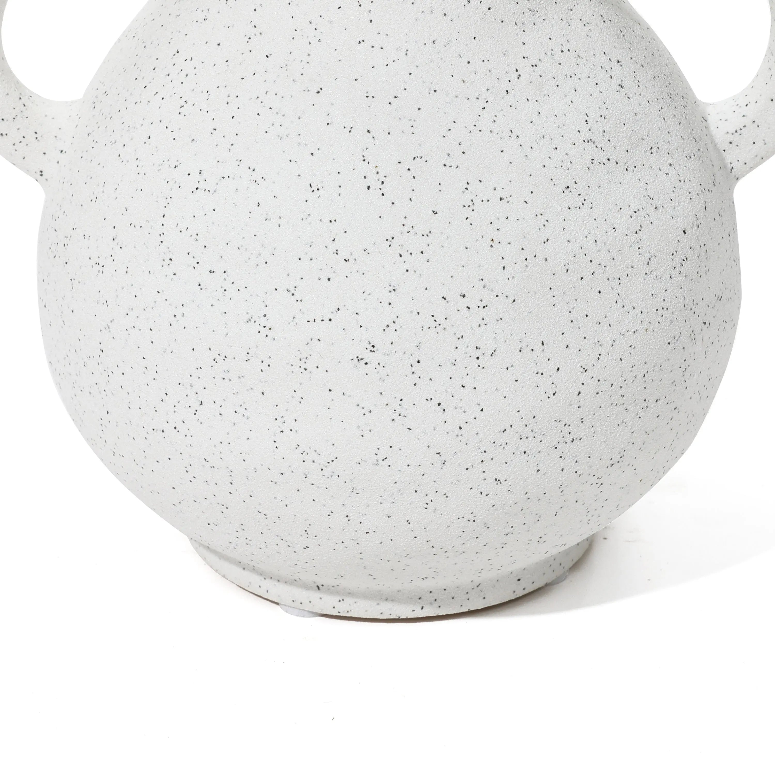 Close-up of a white, speckled ceramic pot with rounded handles, showcasing its textured surface and hinting at a vintage-inspired vase design.