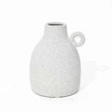 A vintage-inspired design emerges in this speckled white ceramic vase, featuring a rounded body and a loop handle on one side, set elegantly against a plain white background.