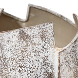 Close-up of a ceramic vase with a textured, speckled surface and irregular, jagged edges, reminiscent of a broken egg design.