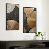 Two abstract art pieces with circular patterns in gold, black, and bronze tones adorn the white wall. Below is a dark table featuring a plant, books, and two white vases. The embossed textures of the frames enhance the overall elegance of this wall decor.