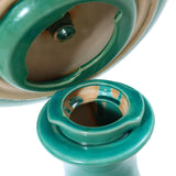 Close-up of a green ceramic tajine with its lid partially lifted, revealing intricate details inside. The tajine has a glossy finish, reminiscent of a decorative garden piece that could complement a ceramic bird bath beautifully.