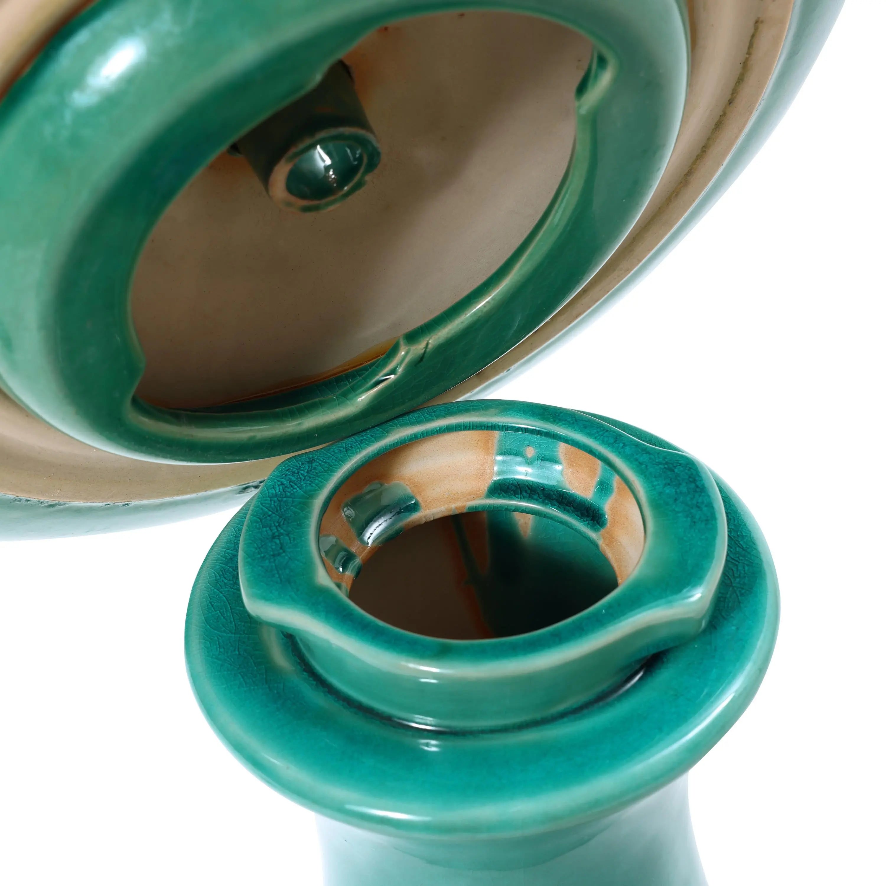 Close-up of a green ceramic tajine with its lid partially lifted, revealing intricate details inside. The tajine has a glossy finish, reminiscent of a decorative garden piece that could complement a ceramic bird bath beautifully.