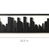 A black, rectangular metal wall art piece featuring a city skyline silhouette, measuring 22.3 inches wide, 6.5 inches high, and 1.5 inches deep, cleverly integrates flip-down hooks to double as a chic wall-mounted coat rack.
.