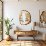 A modern, minimalist room showcases organic decor with a wooden console table adorned with vases, a mirror, framed artwork, and a floor plant. A natural ambiance fills the space as light streams in through a large window, highlighting the table lamps subtle glow.