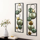 The LuxenHome Glam dishes metal wall art, set of 2, features circular teal and gold designs with metallic finishes. Perfect for a modern setting, they are displayed on a light wall beside a minimalist white vase with a delicate plant, enhancing the sleek decor.