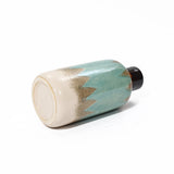 A ceramic vase on its side with a light blue and beige gradient design, featuring a black rim at the top. This coastal-inspired vase adds a touch of nautical charm to your tabletop decor.