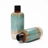 Two ceramic vases with a teal zigzag pattern exude nautical charm. One vase stands upright, while the other lies on its side, both showcasing a dark, narrow neck. Perfect tabletop decor for adding a coastal-inspired touch to any space.