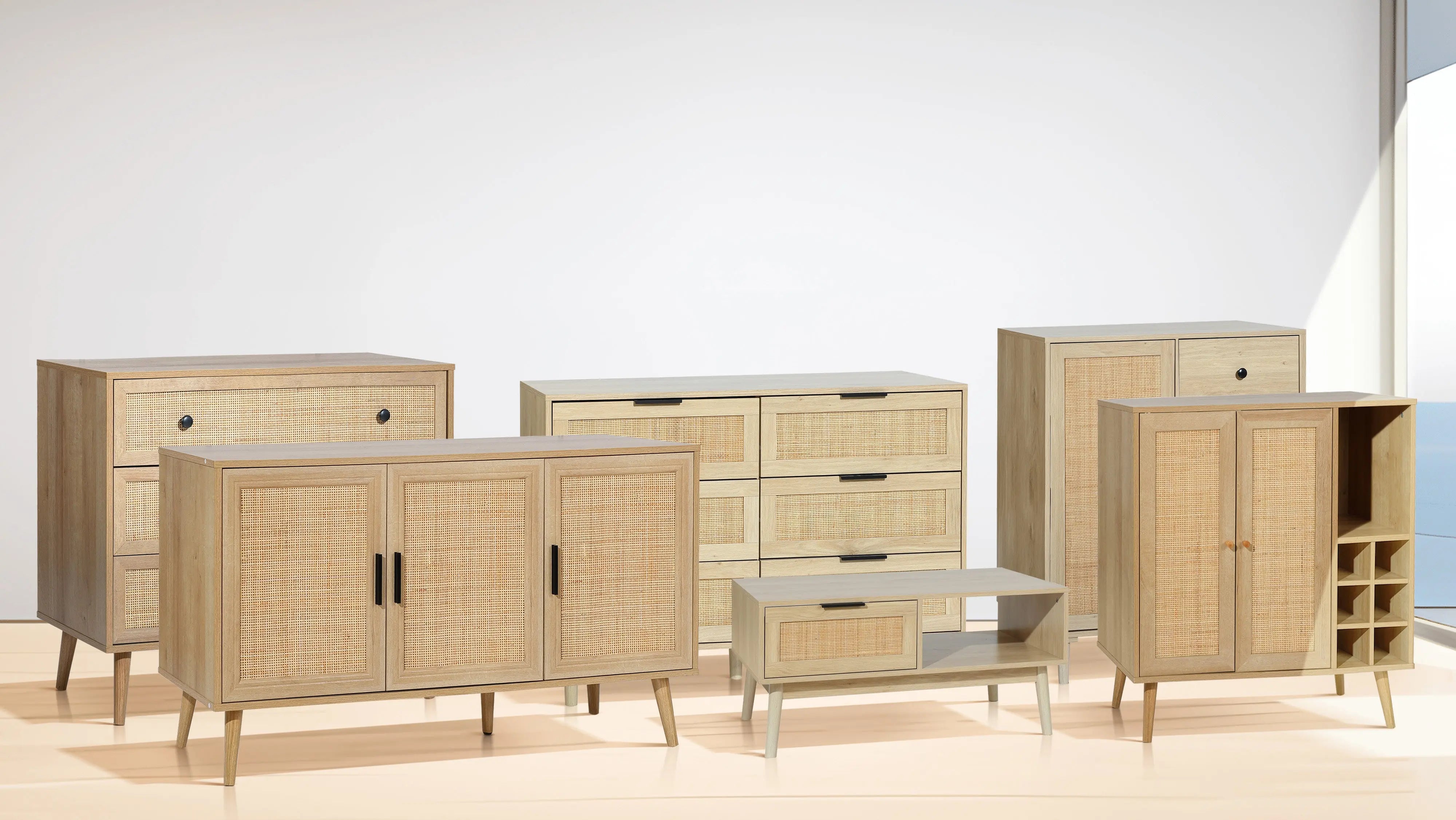 A set of six light wood furniture pieces, including dressers, cabinets, and a coffee table, displayed in a bright room with a view of the ocean through a large window.