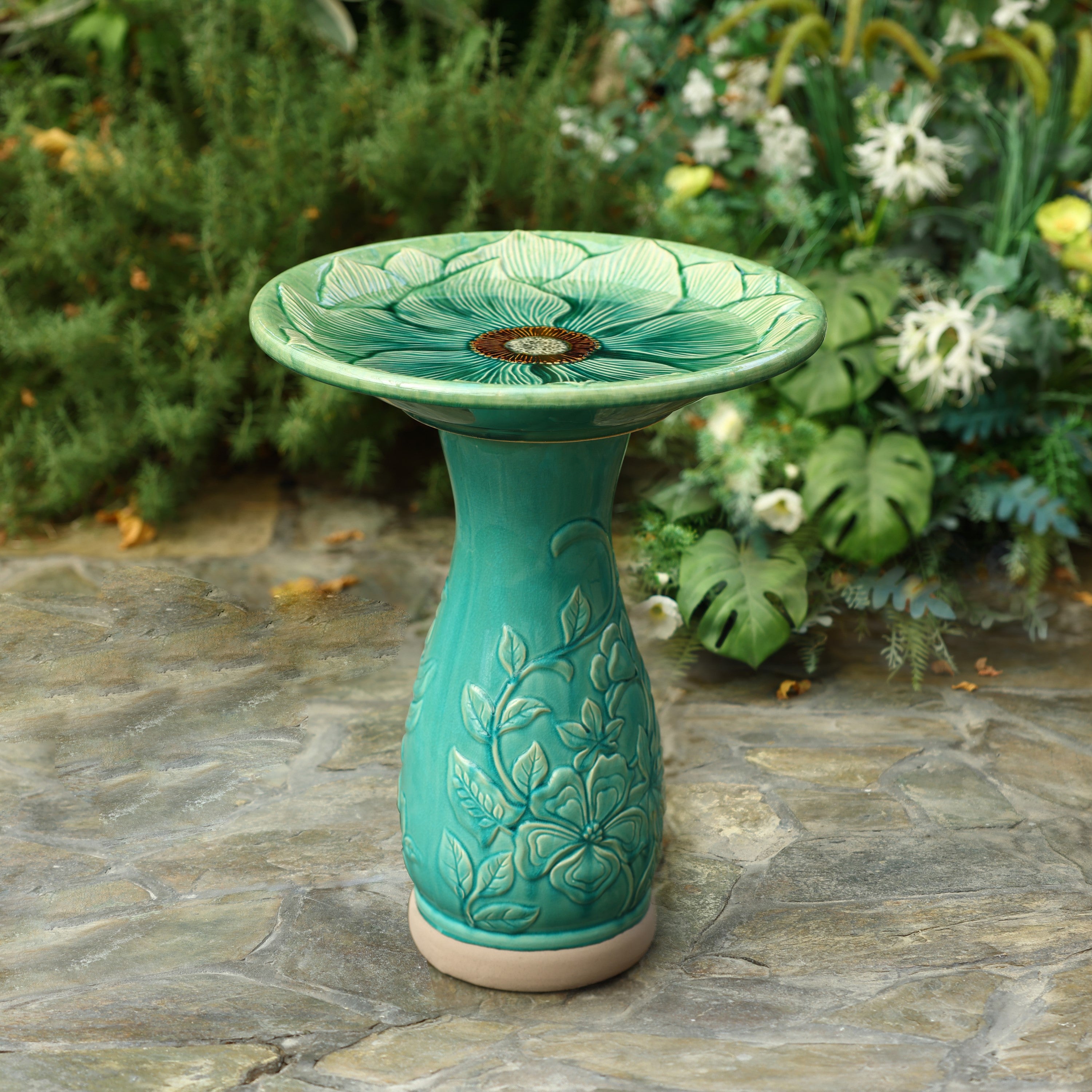 green ceramic birdbath on the ground in backyard