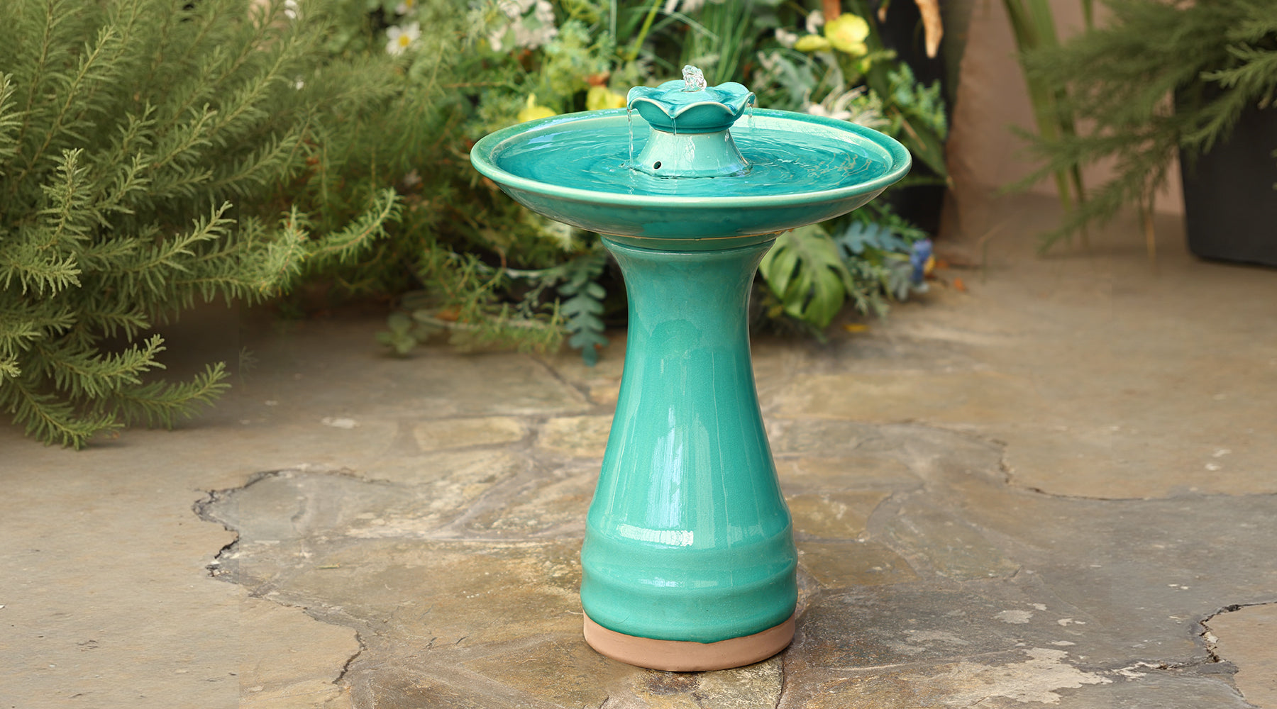 green ceramic birdbath on the ground in backyard