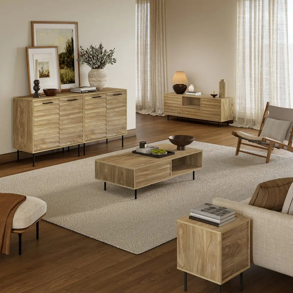 A modern living room with light wood furniture, a beige rug, neutral decor, and large windows with sheer curtains letting in natural light.