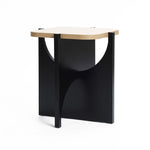 The LuxenHome Bernard side table combines a modern design with a manufactured wood top and black angular supports. It features a geometric pattern with semicircular cutouts on the sides, all set against a classic white background.