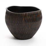 The LuxenHome dark brown textured resin round planter, large, features a ribbed pattern and geometric flair. Its asymmetric wavy top contrasts with the glossy interior, creating a unique design that sits elegantly on a white background.