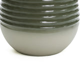 Close-up of the lower half of a round, glossy ceramic vase with a ribbed design. The color transitions from dark green at the top to light beige at the bottom, reminiscent of a modern fountains gentle flow.