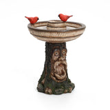 This polyresin garden birdbath serves as a charming outdoor decor centerpiece, boasting a tree trunk base with a carved old man face. Two red bird figurines elegantly perch on the edge, adding whimsical charm to your garden.