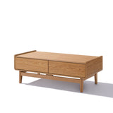 The Eric oak finish coffee table by LuxenHome showcases a sleek, minimalist design with mid-century flair. It features two drawers and stands on short legs, casting a shadow against a white background.