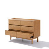 The LuxenHome Eric dresser features a minimalist design with four closed upper drawers and two open lower spaces for ample storage. Crafted from walnut wood with a natural finish, it stands on four legs, reflecting mid-century modern style against a white background.