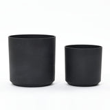 Two black cylindrical planters of different sizes are placed side by side on a white background, showcasing their durable design ideal for outdoor use.