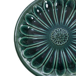 Green ceramic plate with a flower pattern radiating from the center, enhanced by petal-shaped ridges and a glossy finish, perfect for sprucing up your outdoor space or serving small treats beside your garden birdbath.