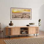 A modern living room showcases a wooden console with a vase, book, and bowls. Above it hangs a large cityscape photo at sunset. A patterned rug accents the floor, complemented by a mid-century modern TV cabinet seamlessly integrating style and function.