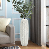 A LuxenHome Modern geometric pattern resin tall vase, 25 h, holds eucalyptus beside a gray sofa. The rooms light blue walls with white paneling and dark curtains complement the wooden floor, adding warmth to the modern, elegant decor.