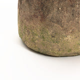 Close-up of a textured, weathered stone surface with patches of mossy green and brown hues, reminiscent of a rustic cement vase.