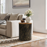 A cozy living room corner with a beige sofa, a black and gold table featuring a hammered iron base adorned with decor, and a vase of roses. Theres a framed landscape on the wall and a patterned rug on the floor.